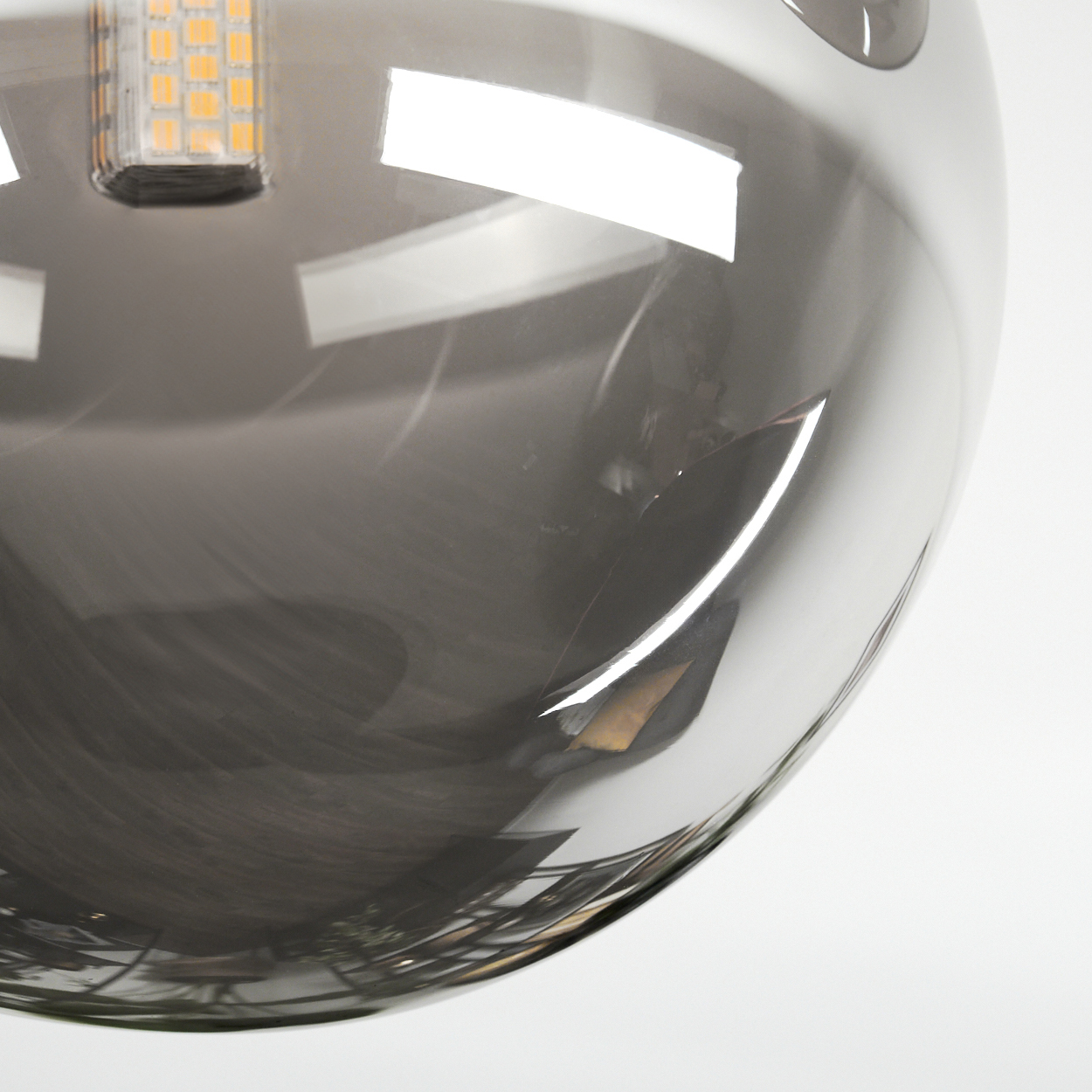 Nahaufnahme einer grauen, kugelförmigen Leuchte mit rechteckiger LED-Komponente oben, die Licht reflektiert.