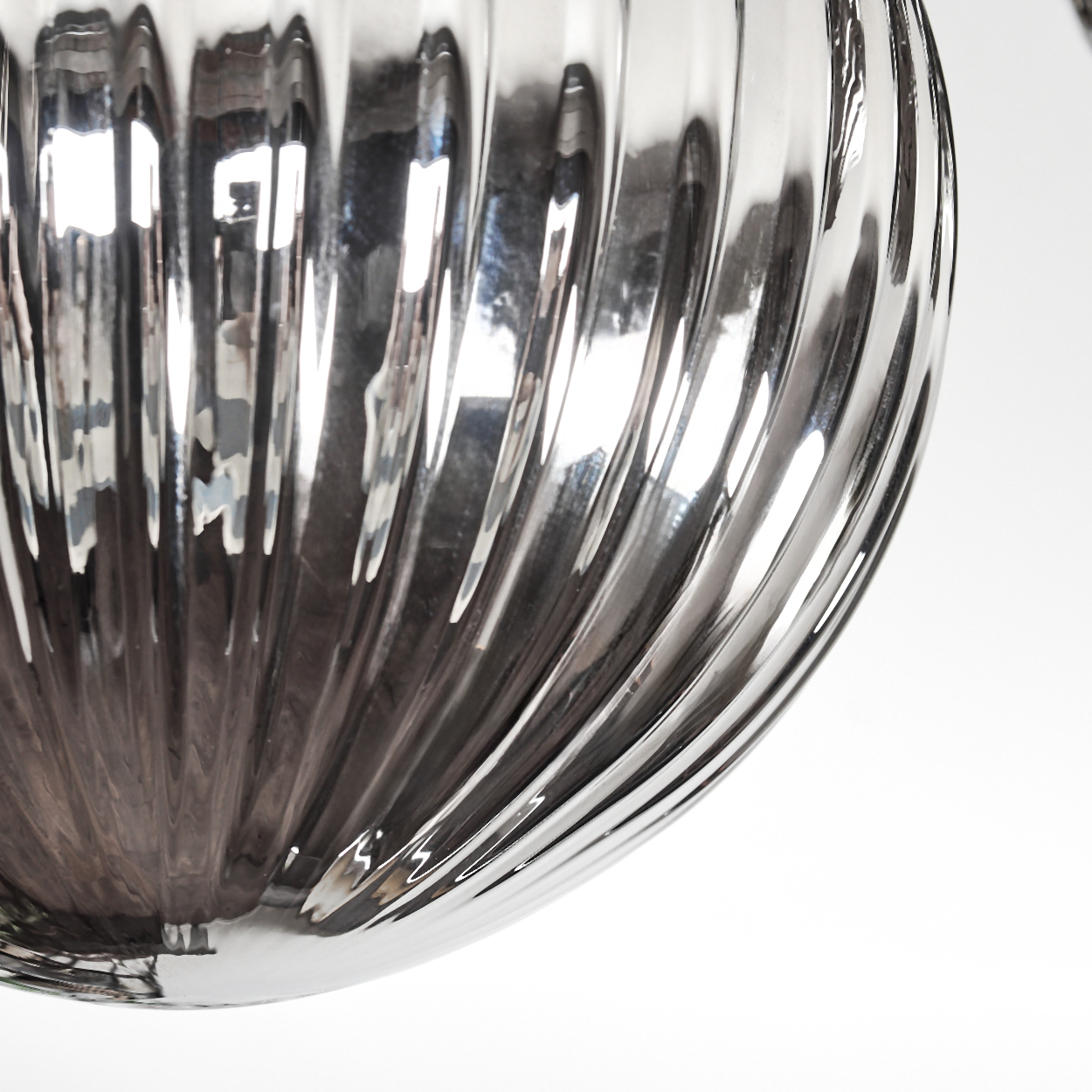 Nahaufnahme eines klaren, geriffelten Glasobjekts, das Licht reflektiert. Der Hintergrund ist weiß. Das Glas hat eine gebogene, abgerundete Form.