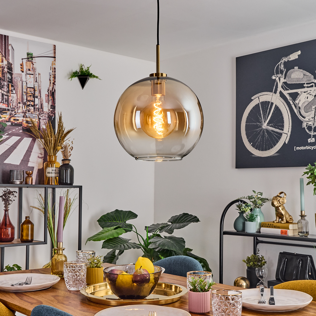Ein Esszimmer mit Hängelampe, Tisch mit Tellern und Gläsern sowie verschiedenen Dekorationsartikeln.
