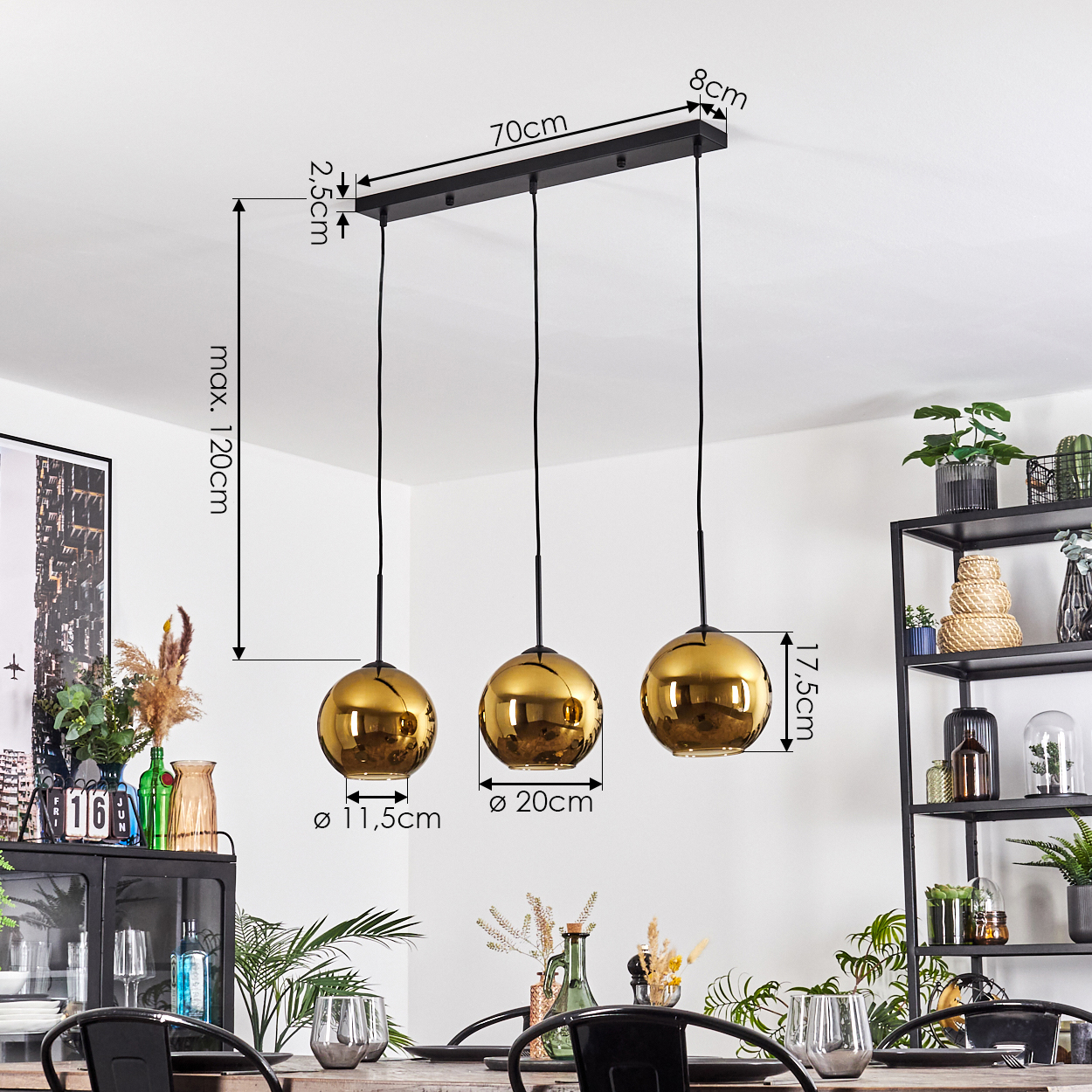 Drei goldene Pendelleuchten hängen über einem Tisch. Abmessungen sind mit schwarzen Linien angegeben. Hintergrund hat ein Regal mit Pflanzen.