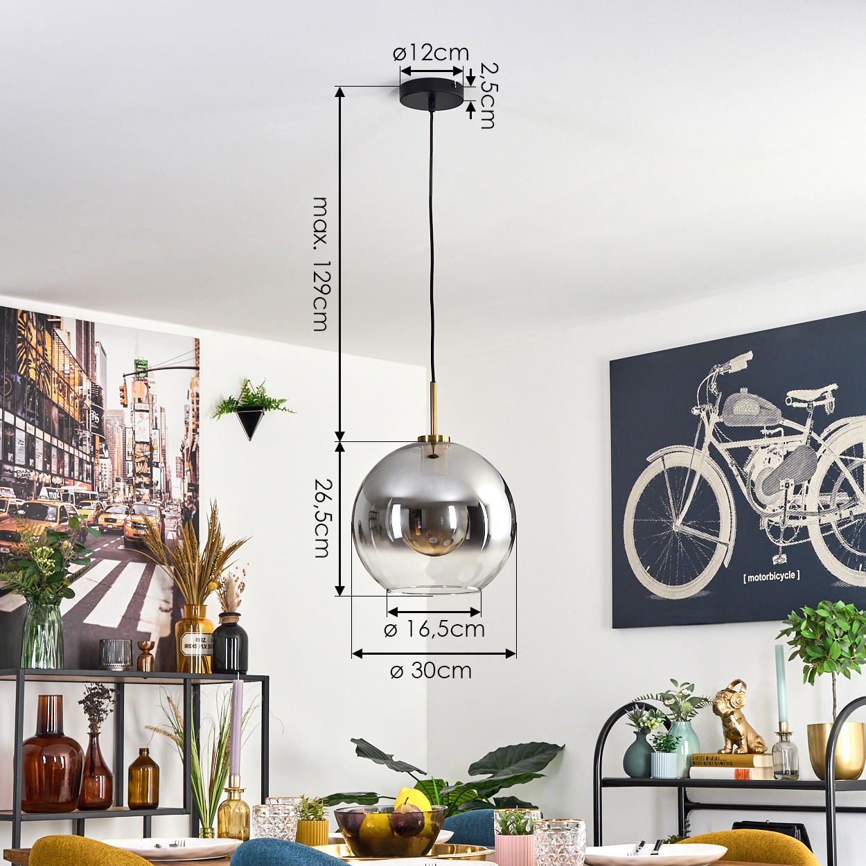 Eine moderne Pendelleuchte mit metallischem Globus, Abmessungen angegeben. Die Szene umfasst eine Tischdekoration und Wandkunst mit einem Motorrad.