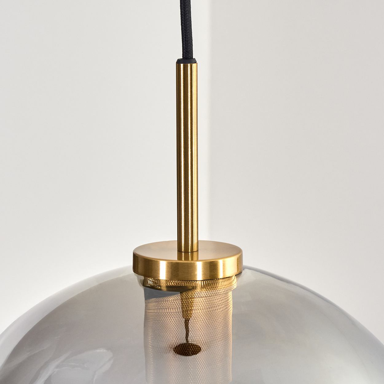 Eine moderne Pendelleuchte mit goldenem Schaft und rauchfarbenem Glasschirm. Das schwarze Kabel hängt von oben, der Hintergrund ist weiß.