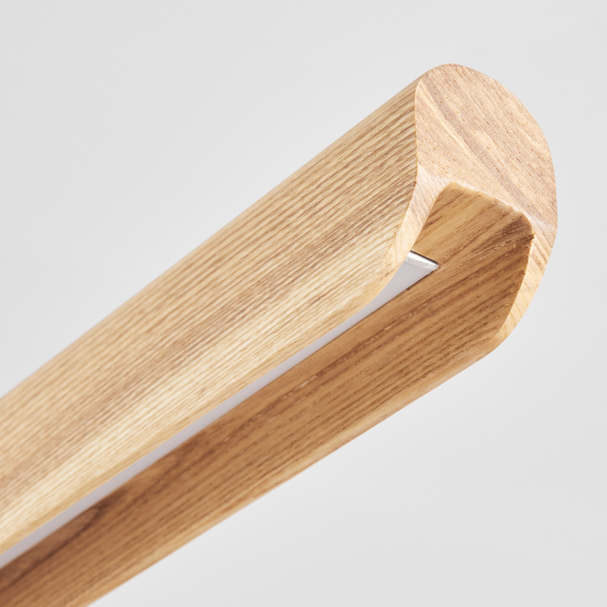 Nahaufnahme eines Holzträgers mit abgerundeten Kanten. Ein dünner, weißer Lichtstreifen ist am Innenrand sichtbar. Hintergrund ist weiß.