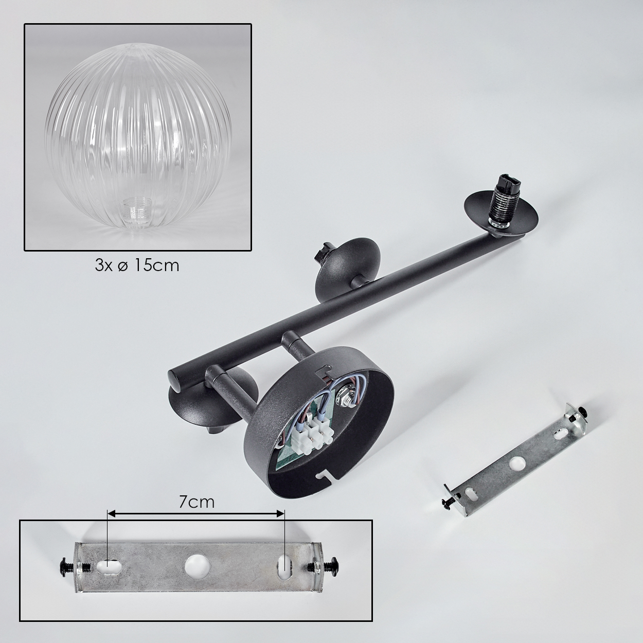 Das Bild zeigt zerlegte Teile einer schwarzen Deckenlampe mit einer klaren Glaskugel. Eine Metallhalterung und ein Sockel sind sichtbar.