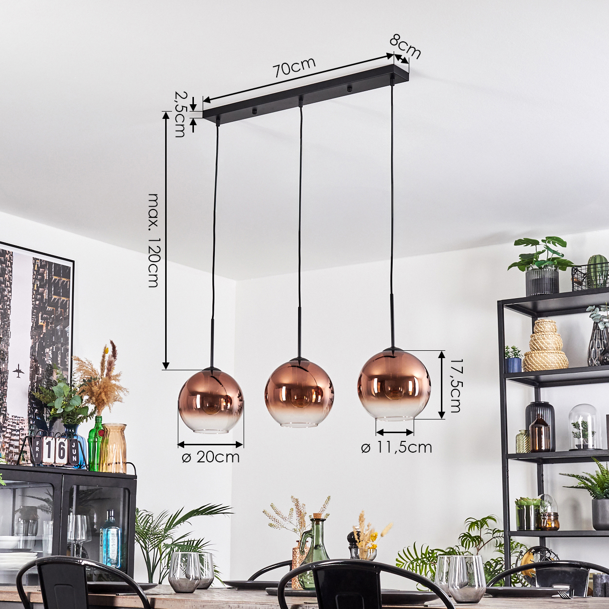 Drei kupferfarbene Pendelleuchten hängen von der Decke. Ein Esstisch ist im Vordergrund, rechts ein Regal.