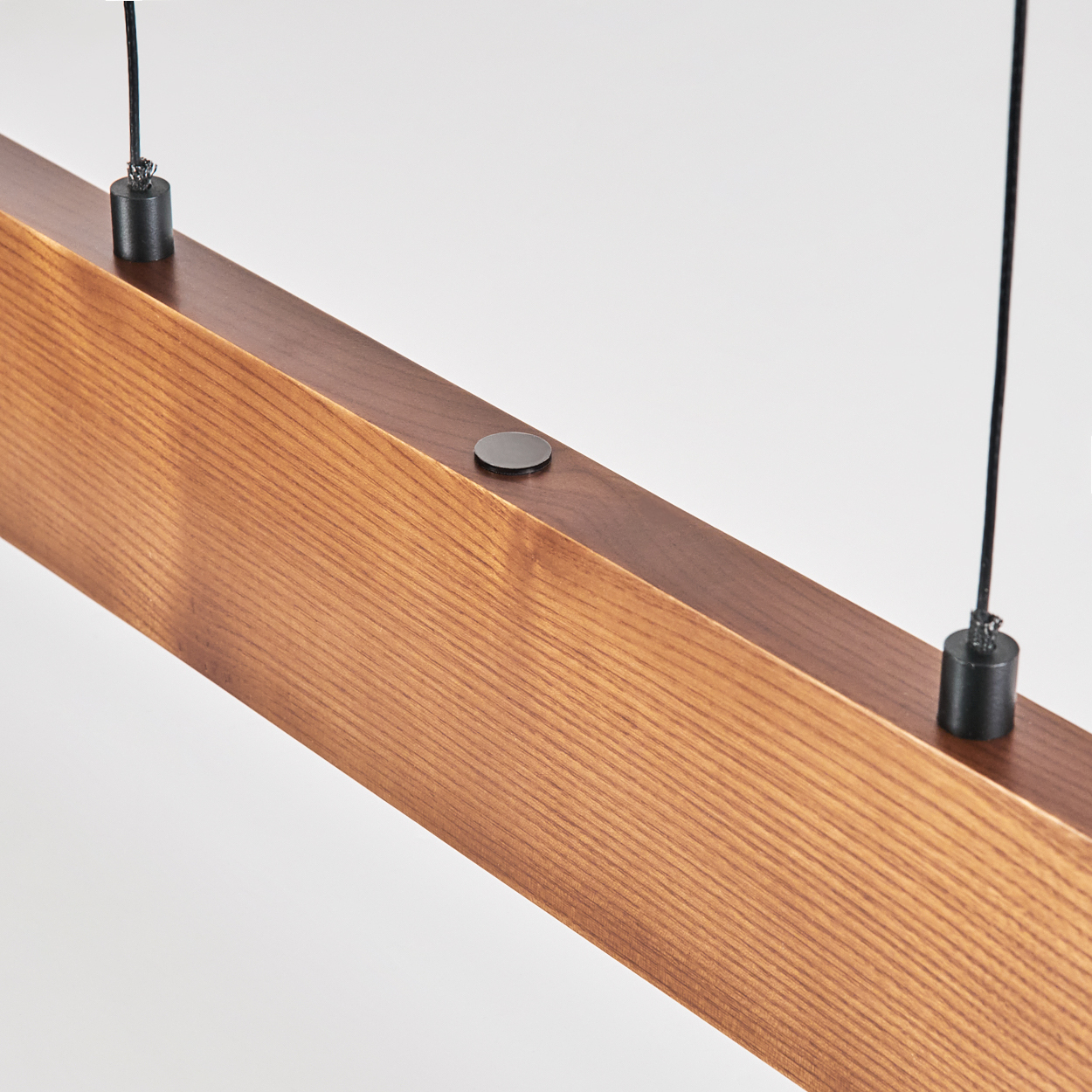 Holzbalken mit Maserung, aufgehängt an schwarzen Drähten, schwarze Metallakzente, vor weißem Hintergrund.