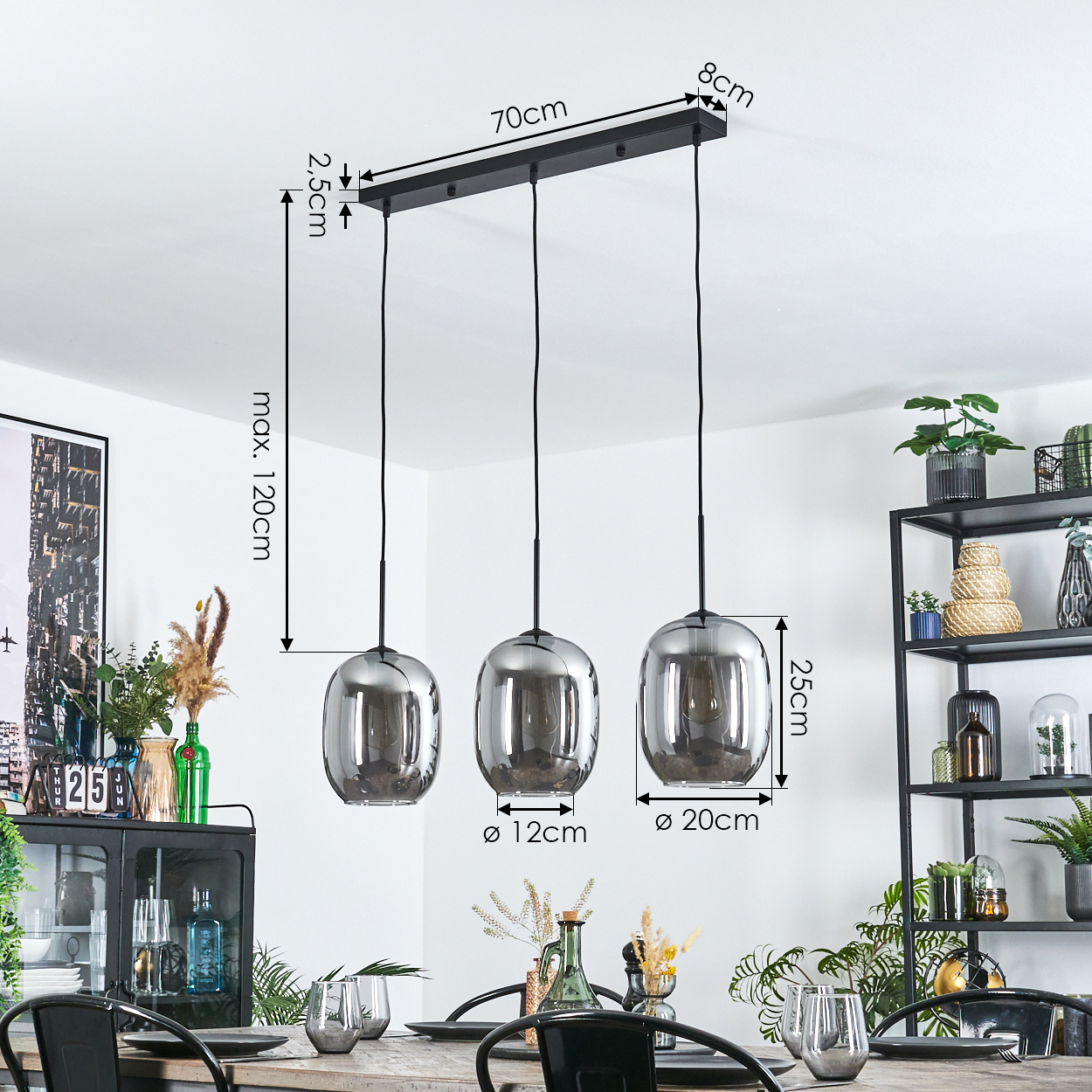 Drei Pendelleuchten mit Glasschirmen hängen über einem Tisch. Abmessungen sind beschriftet. Pflanzen und Dekoration sind im Hintergrund.