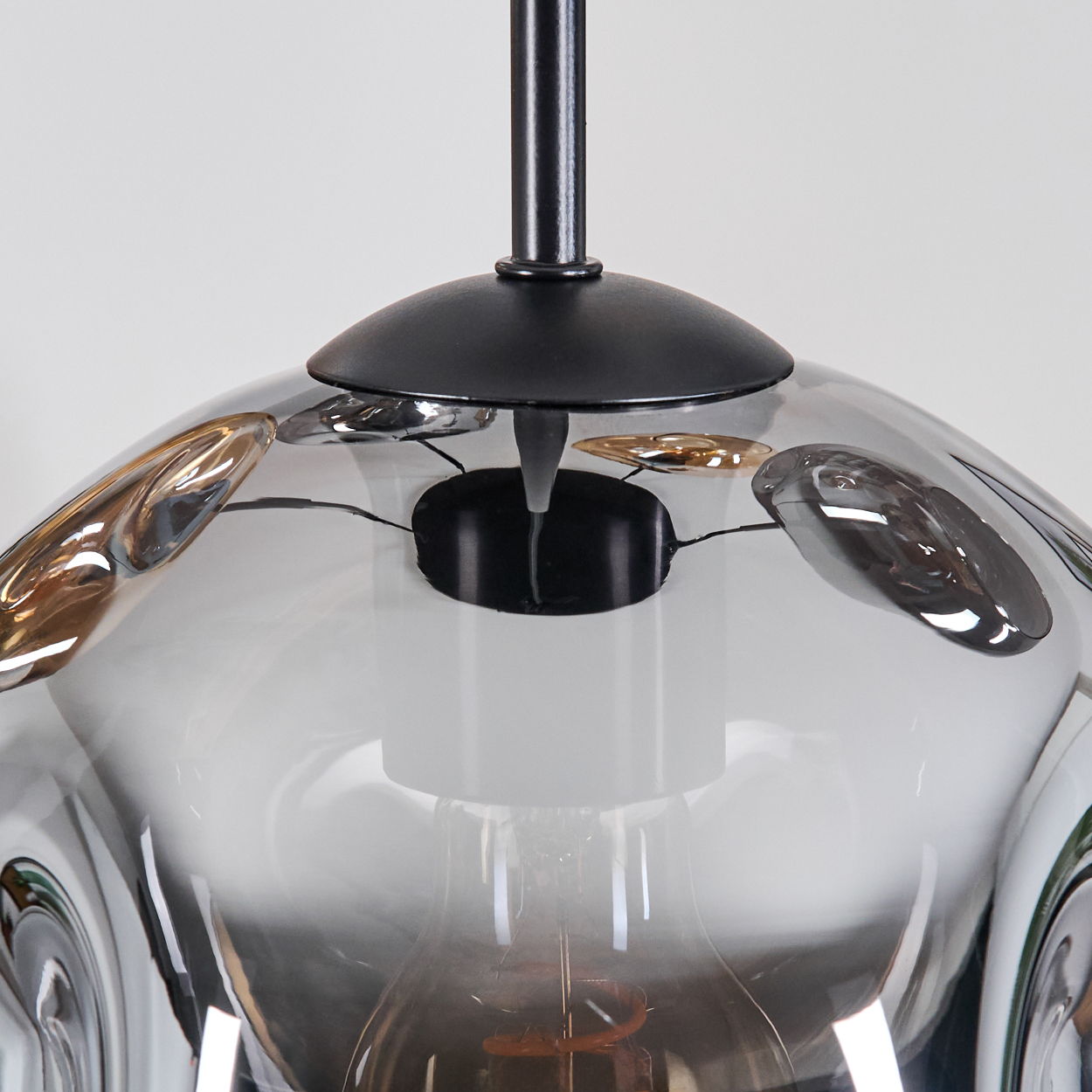 Moderne Glas-Pendelleuchte mit schwarzem Stiel. Der Glasschirm ist grau mit goldenen Akzenten.