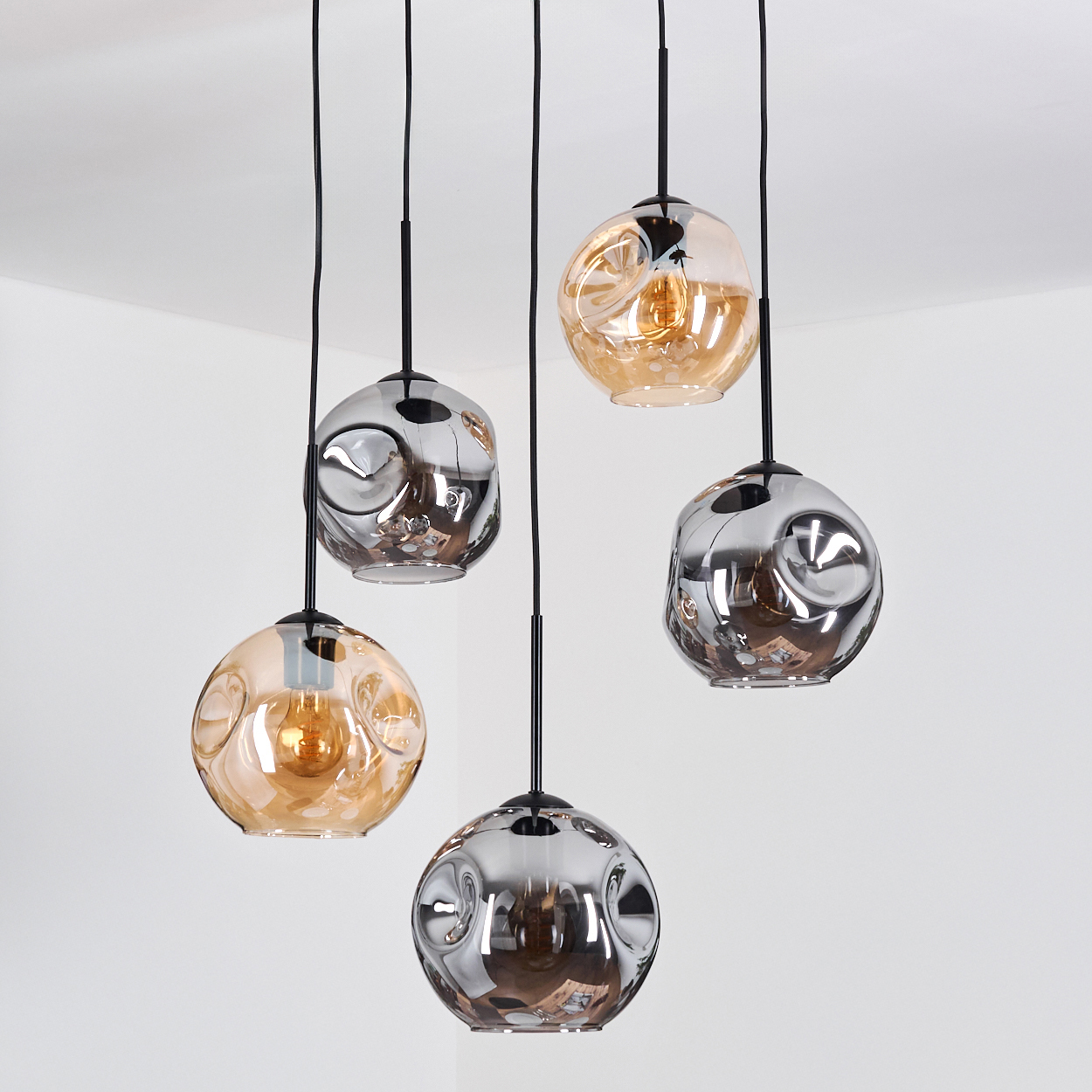 Fünf hängende Pendelleuchten mit blasenartigen Glasschirmen. Einige sind bernsteinfarben, einige silberfarben, alle mit schwarzen Kabeln vor weißem Hintergrund.