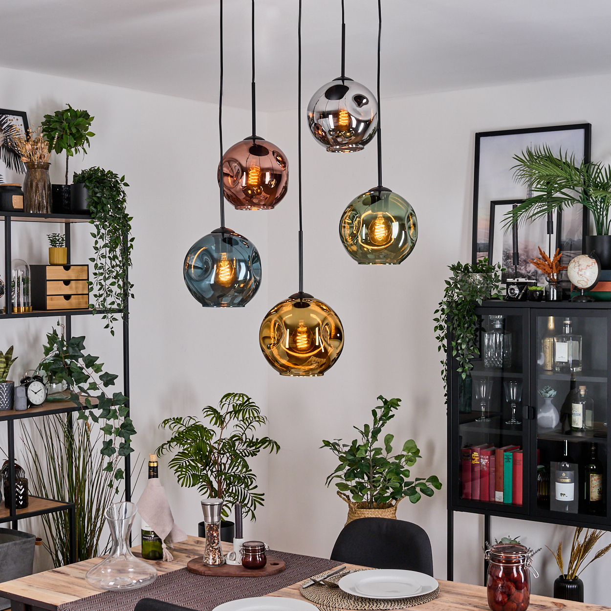Esszimmer mit Holztisch, Hängelampen und Pflanzen. Es gibt auch einen Schrank und ein Regal.
