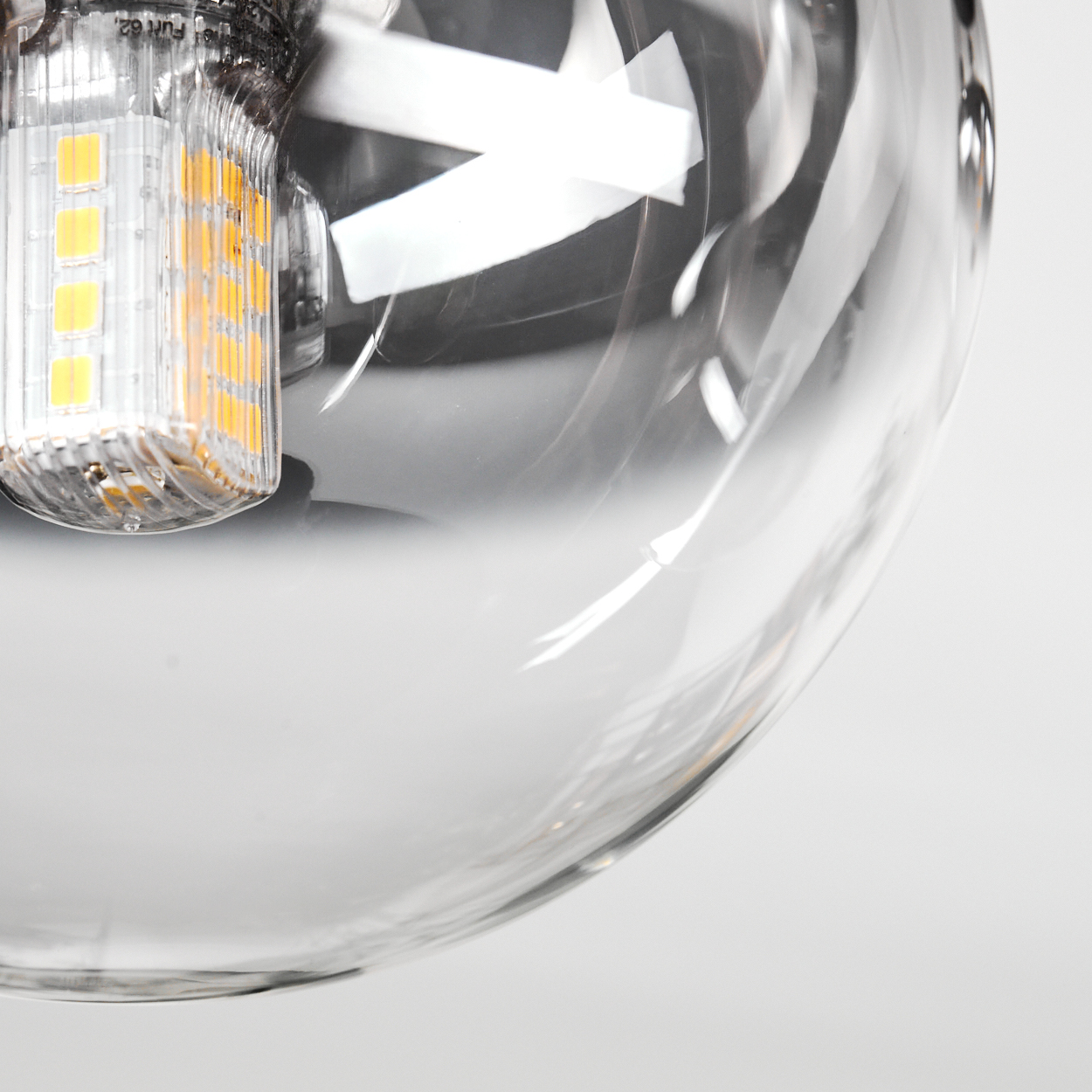 Nahaufnahme einer Glashängelampe mit LED-Lampe. Die Glühbirne ist teilweise sichtbar, der Rest der Lampe ist unscharf.