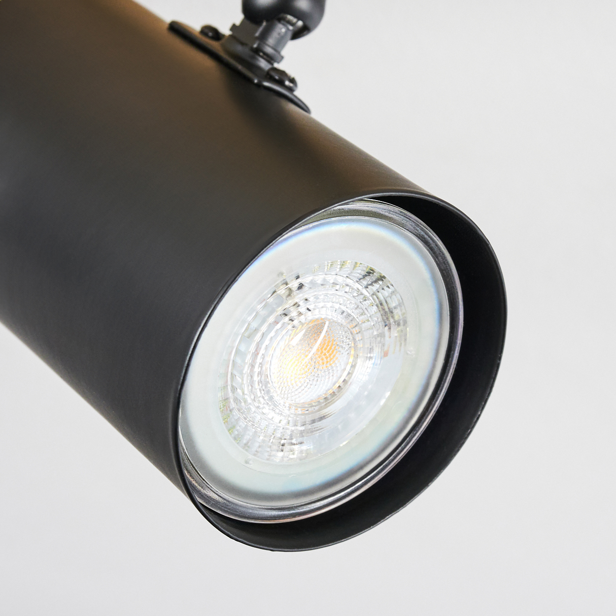 Nahaufnahme eines schwarzen zylindrischen Strahlers mit hellem LED-Licht. Der Hintergrund ist eine weiße Oberfläche.