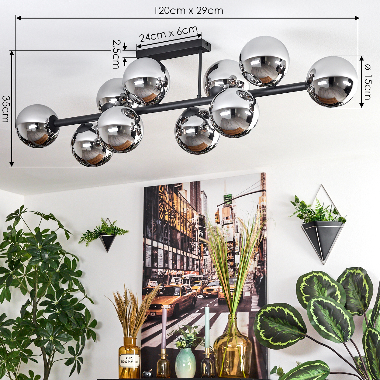 Eine moderne schwarze Deckenlampe mit Chromkugeln. Darunter ein Stadtbildgemälde mit Pflanzen und dekorativen Vasen.