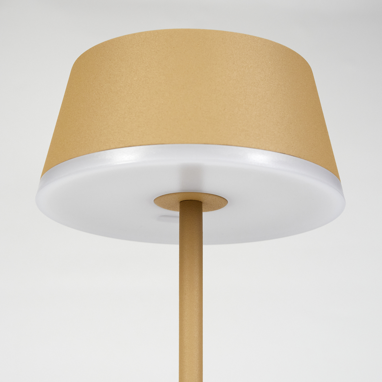 Eine moderne Lampe mit goldfarbenem Lampenschirm und Stiel. Der Schirm hat eine hellbraune Farbe und die Basis ist weiß. Einfaches Design.