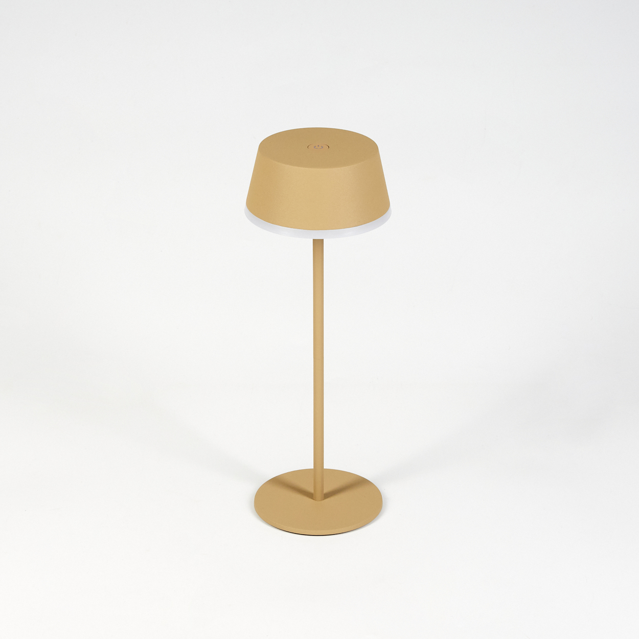 Eine beige Lampe mit rundem Fuß und zylindrischem Schirm steht auf weißem Hintergrund. Der Schirm hat einen weißen Rand.