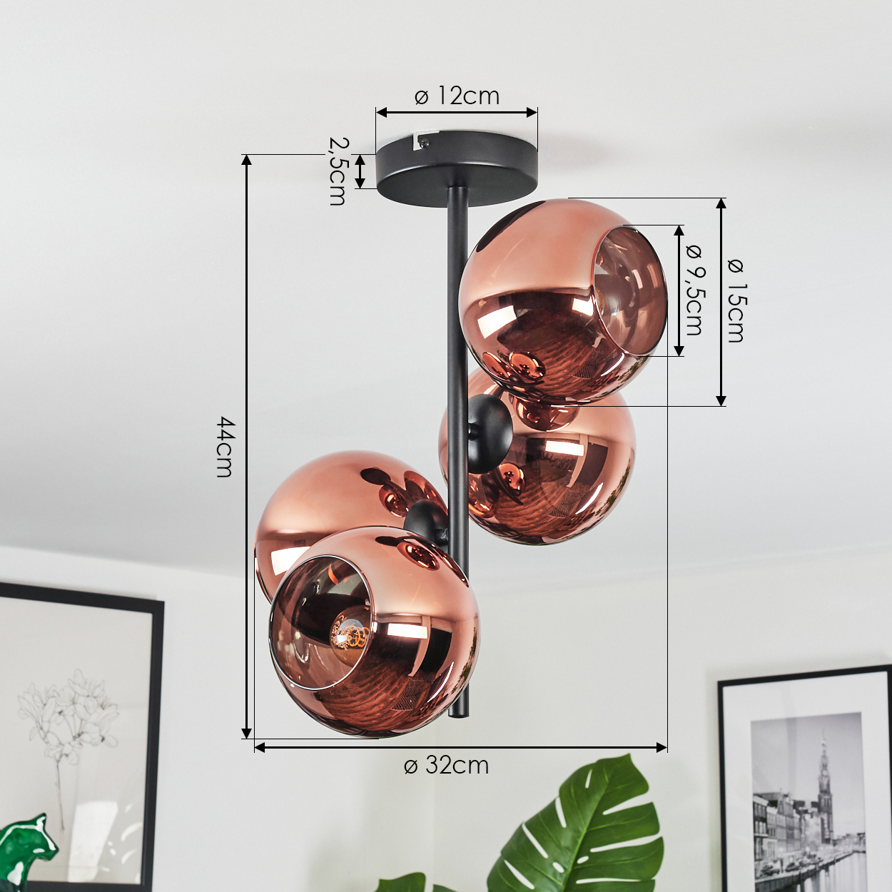 Eine moderne Deckenlampe mit drei kupferfarbenen, kugelförmigen Schirmen. Sie hängt an einer schwarzen Halterung, mit Maßangaben.