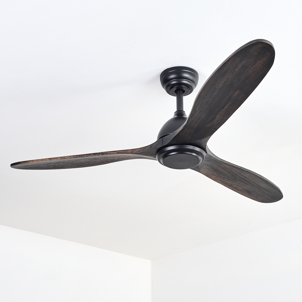Ein Deckenventilator aus dunklem Holz mit drei Blättern vor einer weißen Decke. Der Ventilator ist ausgeschaltet.