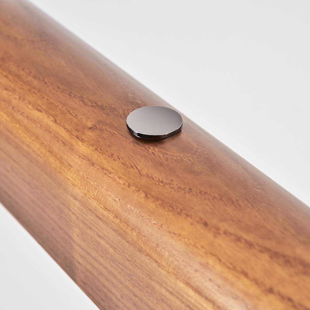Nahaufnahme eines Holzbalkens mit einer kleinen, runden Metallscheibe darauf. Der Hintergrund ist weiß.
