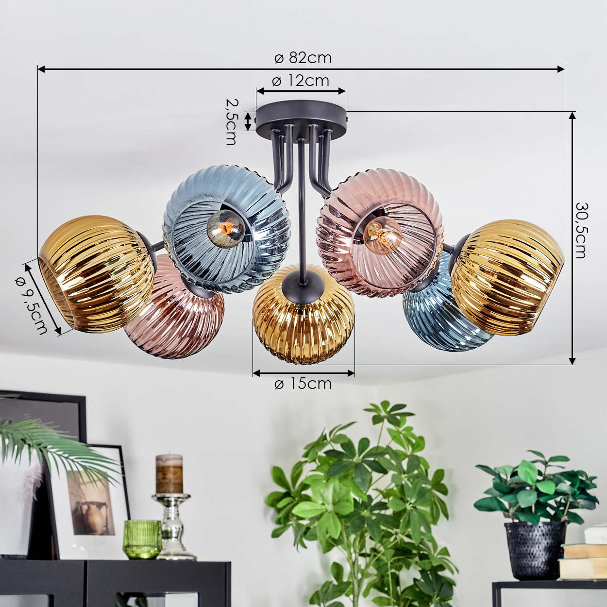 Eine moderne Deckenlampe mit sechs bunten Glaskugeln. Sie hängt von der Decke, mit Pflanzen und Dekoration im Vordergrund.