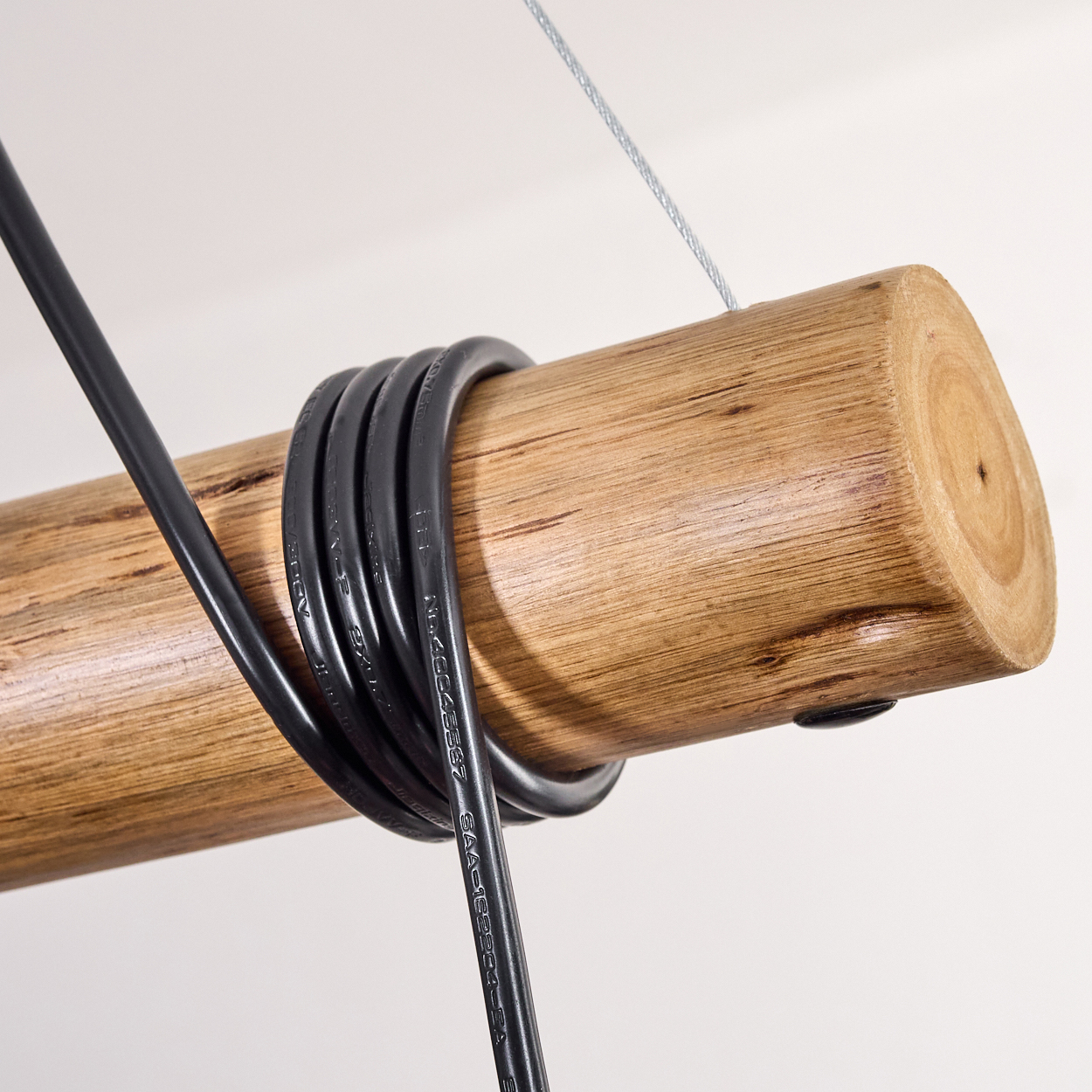 Ein Holzstamm mit schwarzen Drähten. Ein dünnes silbernes Kabel ist befestigt. Der Hintergrund ist weiß.