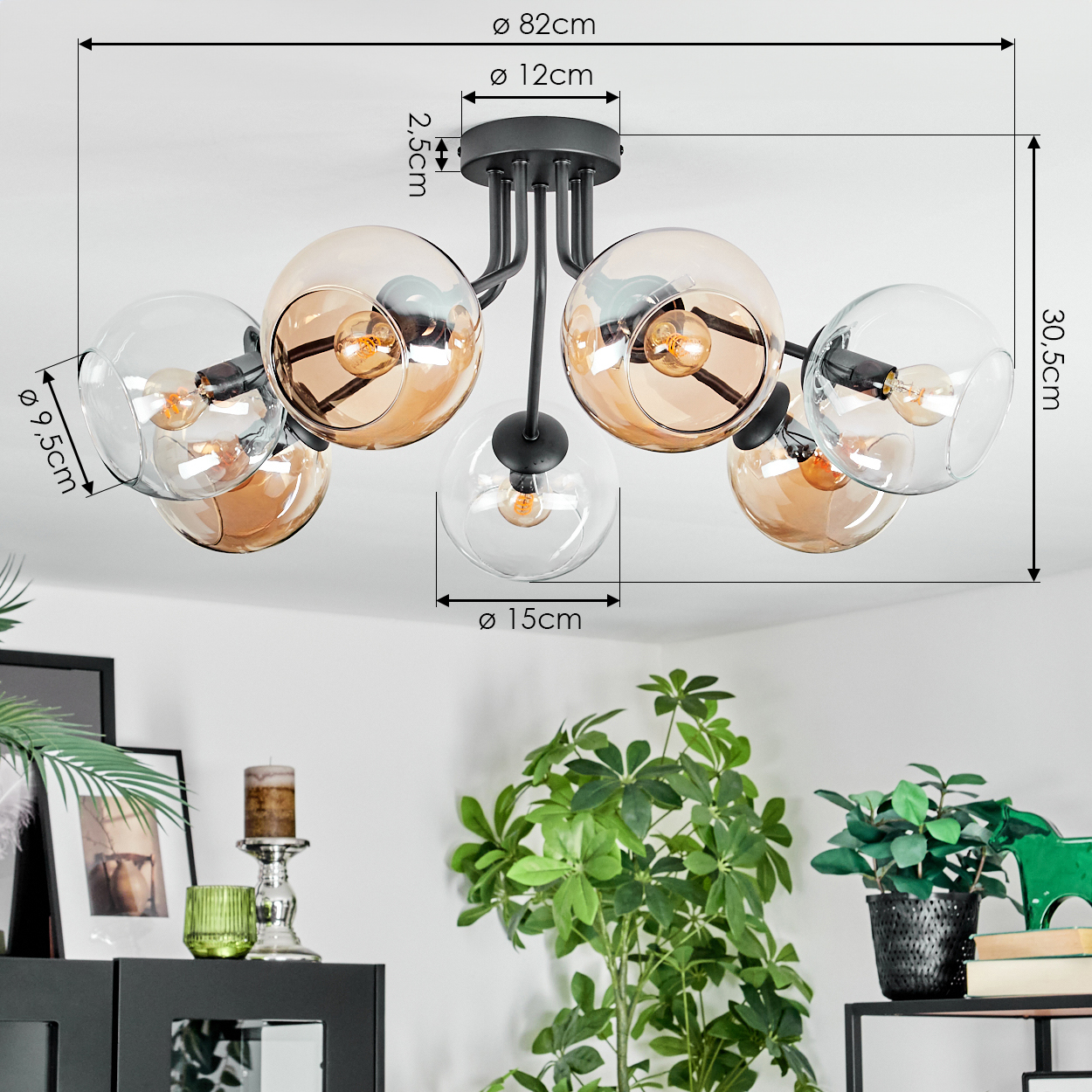 Moderne Deckenlampe mit sechs Glaskugeln. Sie hat beschriftete Maße. Pflanzen und Möbel befinden sich im Hintergrund.