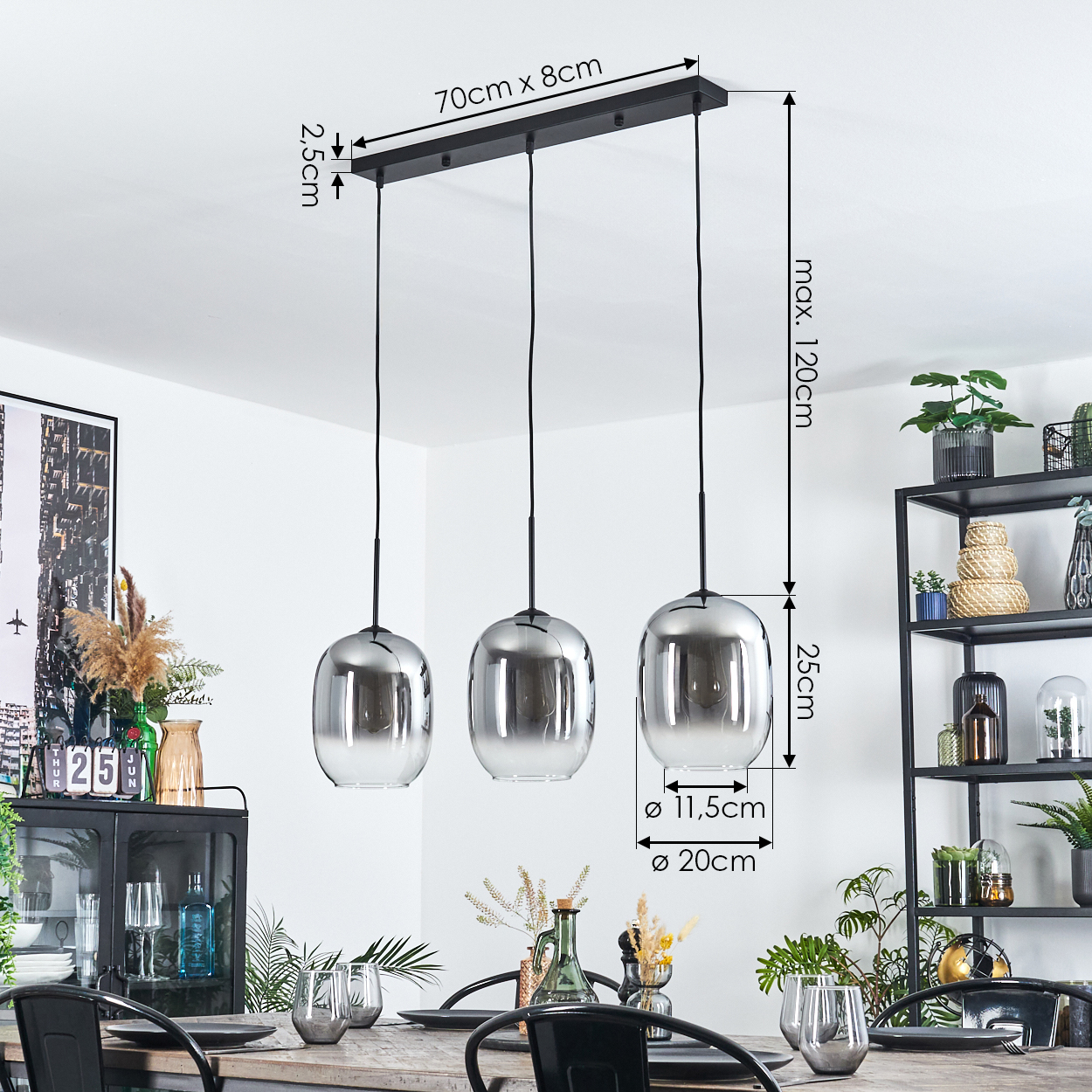 Drei chromfarbene Pendelleuchten hängen über einem Holztisch, der für das Abendessen gedeckt ist. Pflanzen, Regale und Dekoration im Hintergrund.