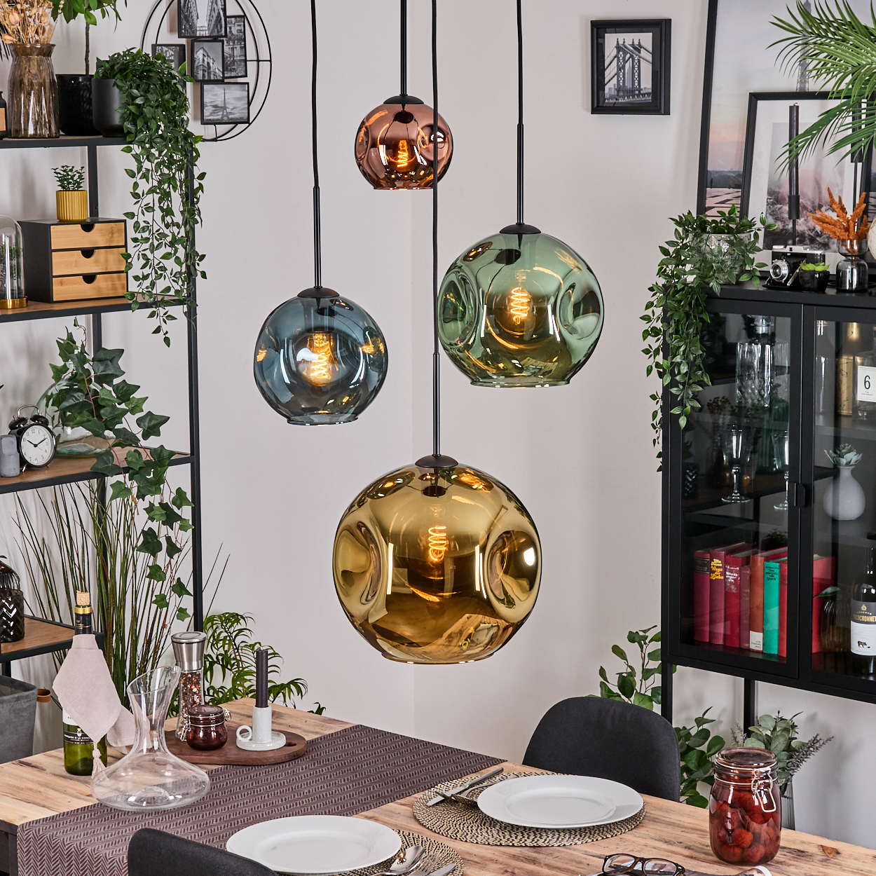 Esszimmer mit vier bunten Pendelleuchten, Tisch mit Tellern und einem Schrank mit Dekorationen.