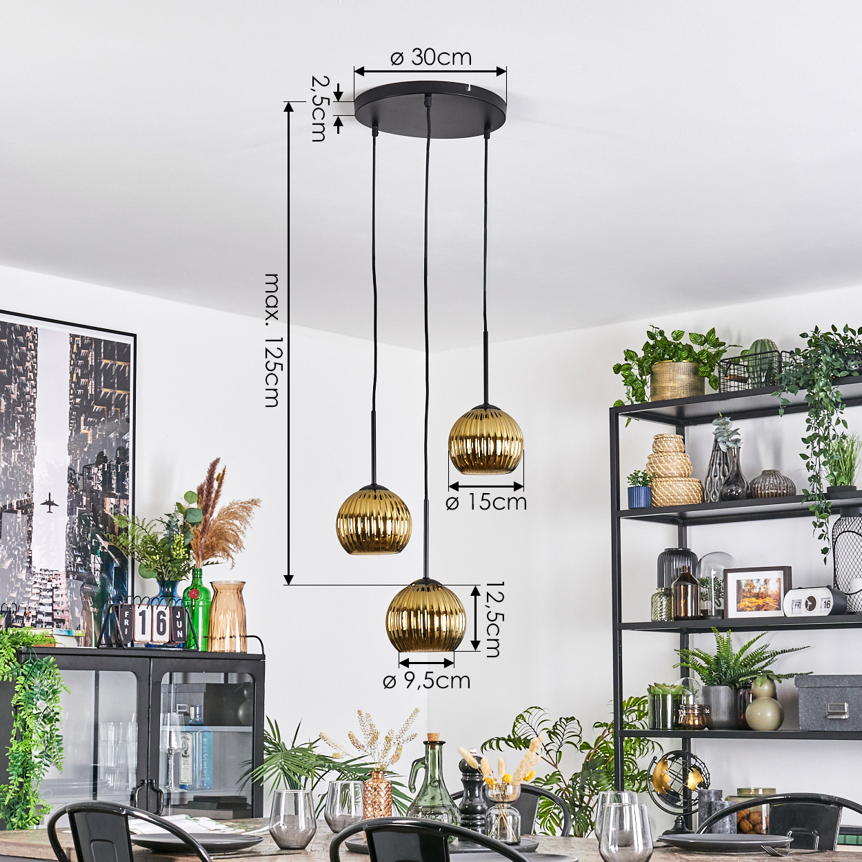 Ein modernes Esszimmer mit einem schwarzen Kronleuchter mit drei goldfarbenen Kugelleuchten. Dekorative Pflanzen und ein Tisch im Vordergrund.