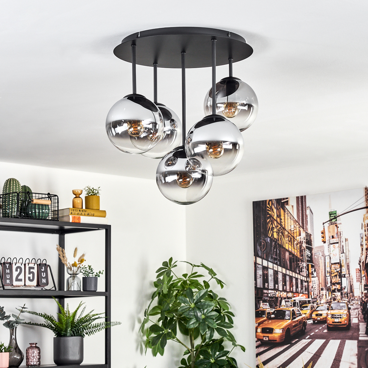 Eine moderne Deckenleuchte mit fünf kugelförmigen Lichtern. Pflanzen und Regale mit Dekoration befinden sich im Vordergrund. Eine Stadtstraßenszene ist im Hintergrund.