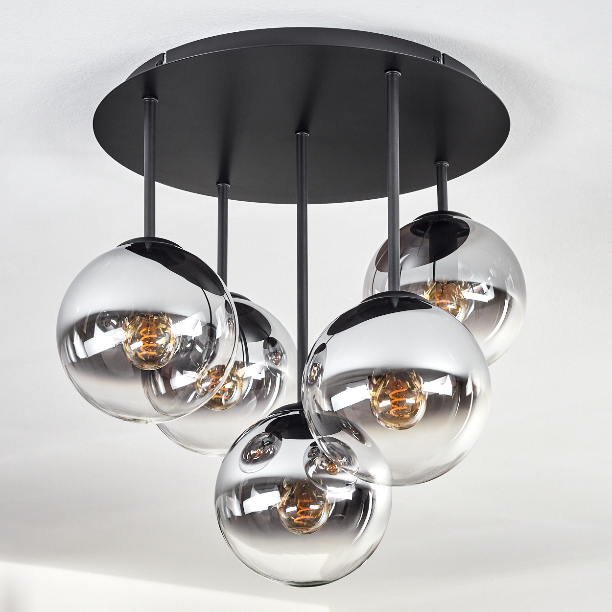 Eine moderne Deckenleuchte mit fünf kugelförmigen, verspiegelten Glasschirmen, die jeweils eine warmtonige Glühbirne enthalten.
