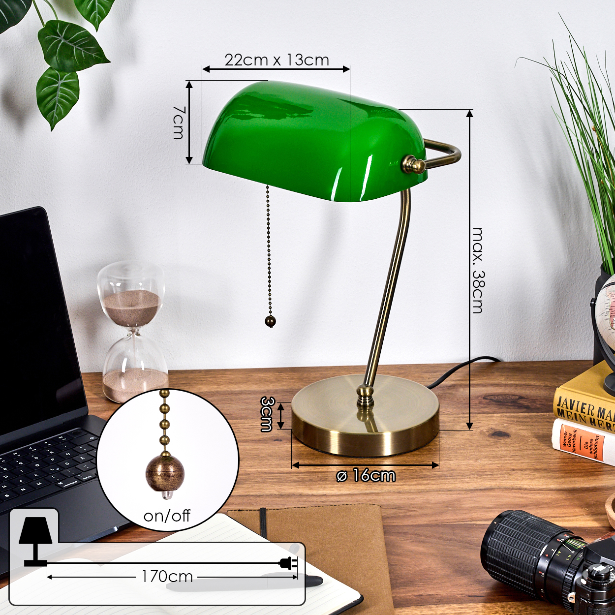 Eine grüne Schreibtischlampe auf einem Holztisch mit Laptop, Sanduhr und Kamera. Abmessungen: 22x13cm, 7cm, 16cm, 38cm, 3cm, 170cm.