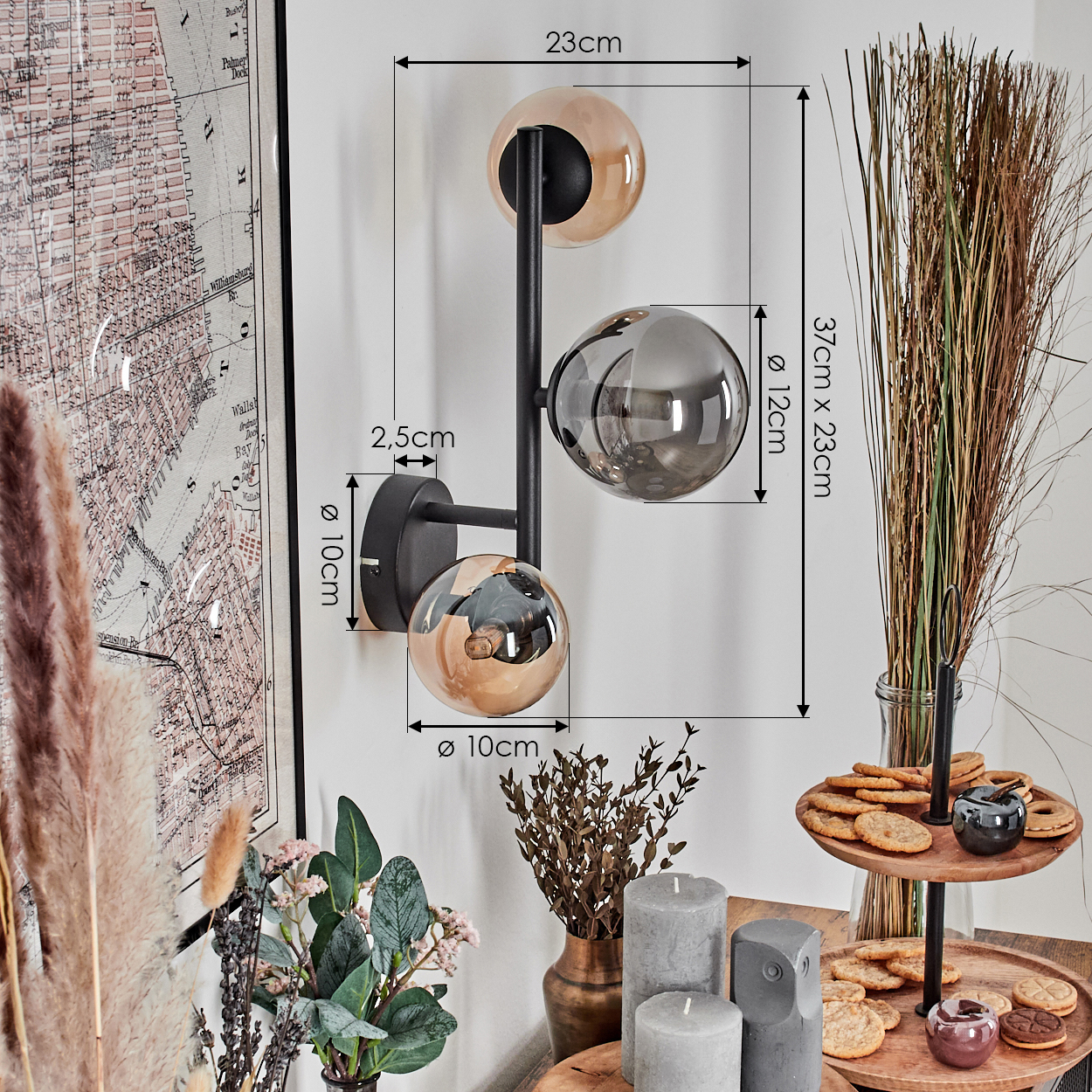 Eine moderne Wandlampe mit drei kugelförmigen Schirmen. Der Raum hat verschiedene Dekorationen, darunter eine Karte, Blumen, Kerzen und Kekse.