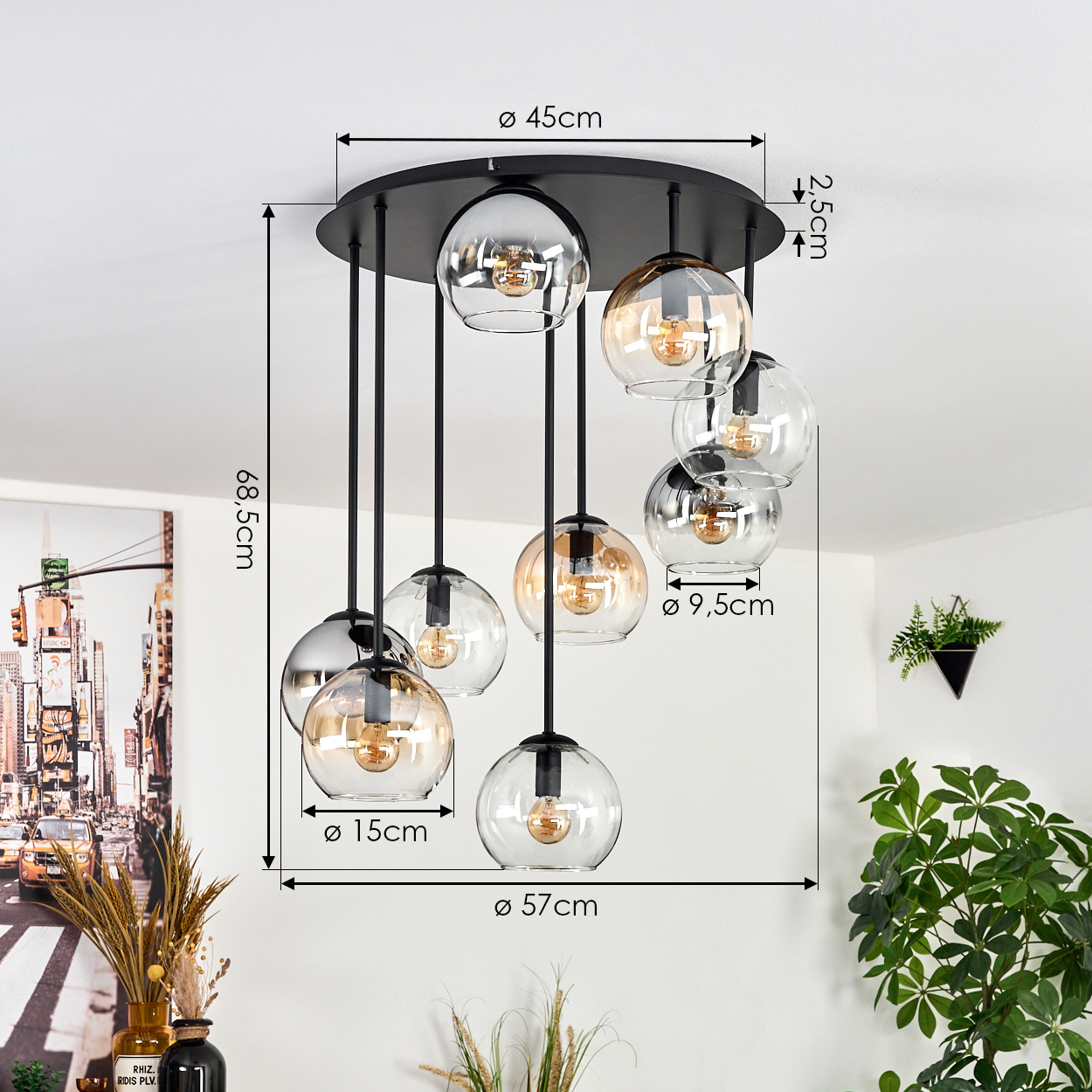Eine moderne Hängelampe mit kugelförmigen Glasschirmen hängt von einer schwarzen kreisförmigen Basis. Abmessungen sind markiert. Eine Pflanze und ein Gemälde sind im Hintergrund.