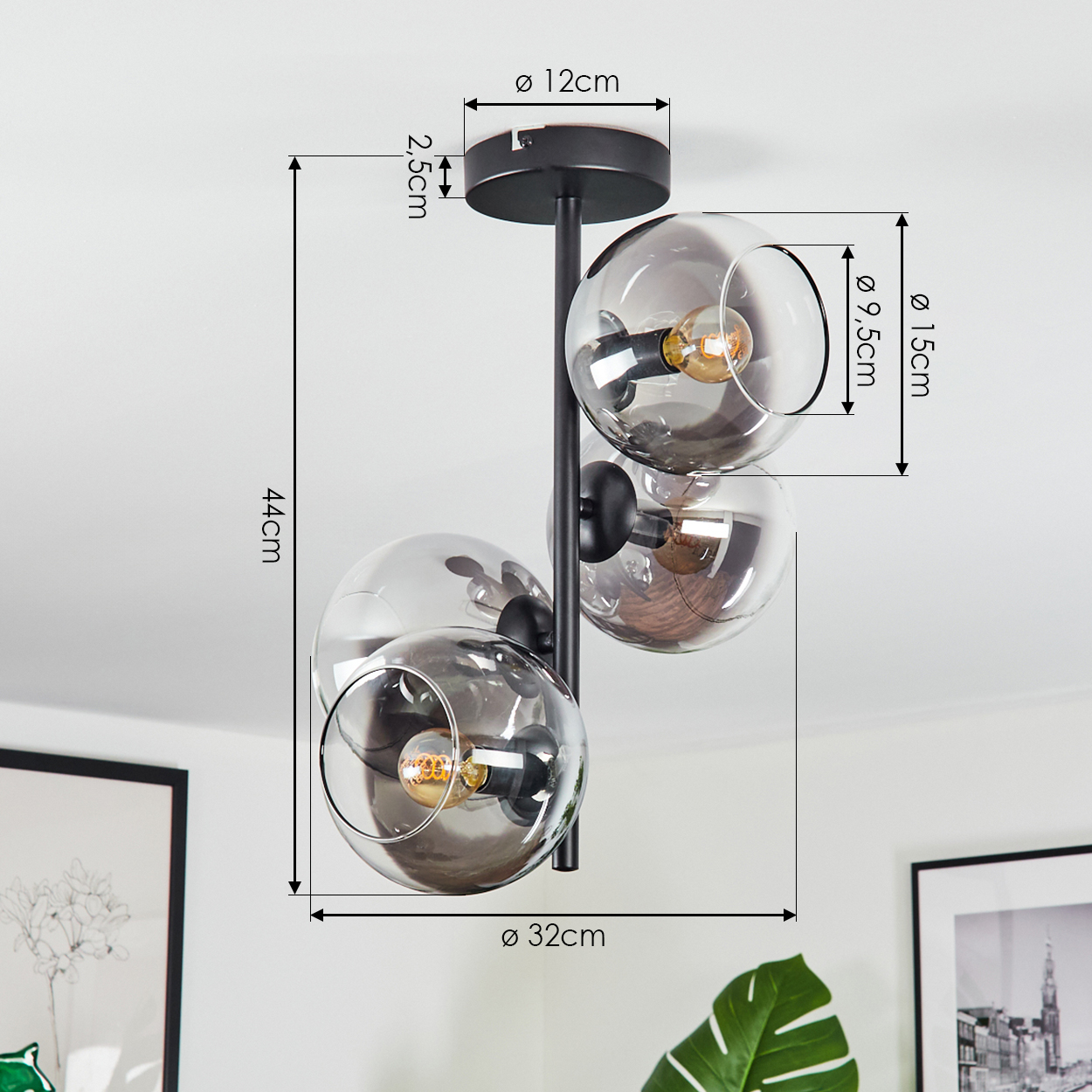 Eine moderne schwarze Deckenlampe mit vier Glaskugel-Schirmen, die jeweils eine Glühbirne enthalten. Abmessungen sind mit Pfeilen und Zahlen angegeben.
