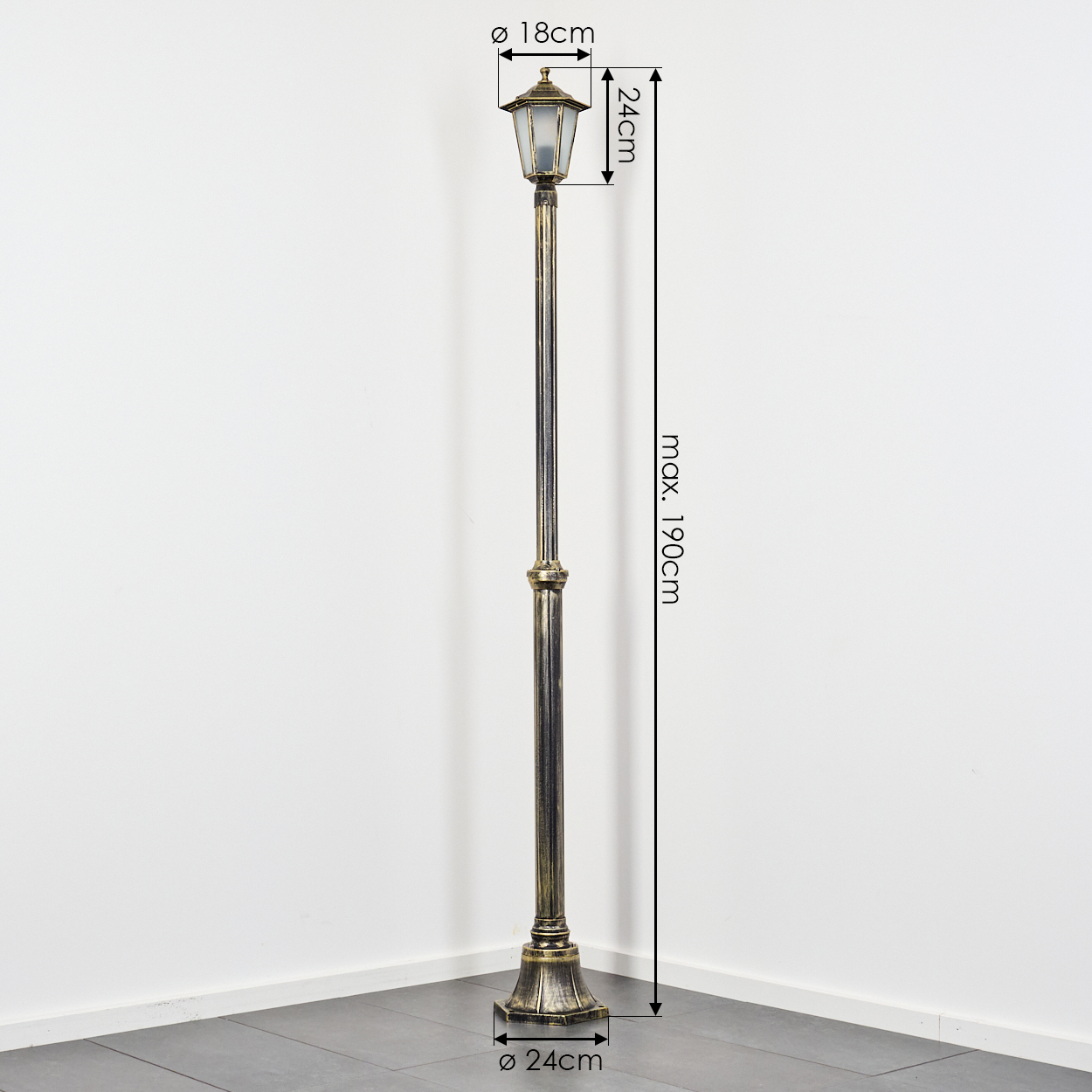 Eine dekorative Außenlaterne im antiken Stil. Sie ist bronzefarben und mit Maßen versehen. Die Lampe steht vor einer weißen Wand und einem grauen Boden.