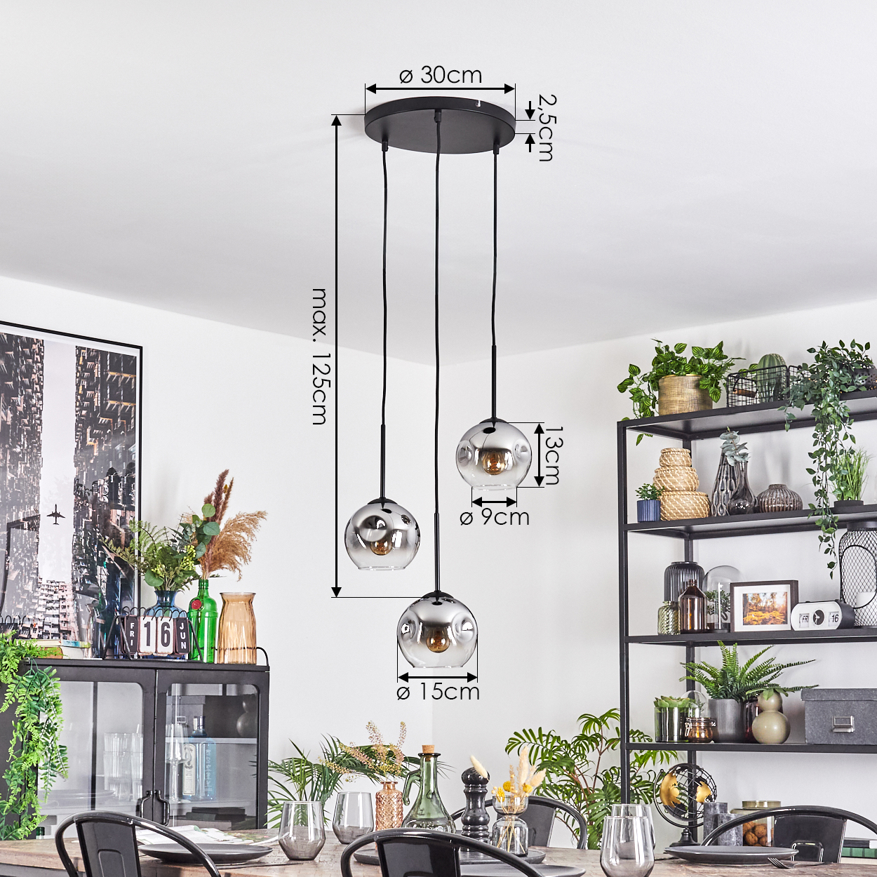 Drei Pendelleuchten mit Glaskugeln hängen von der Decke. Im Vordergrund ein Esstisch, im Hintergrund Pflanzen und Dekoration.