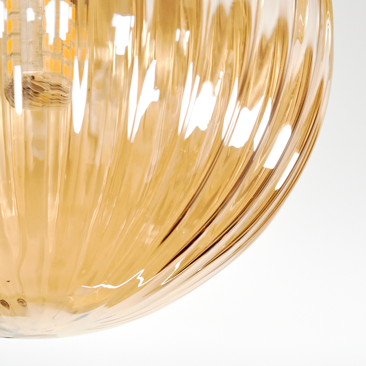 Nahaufnahme eines Lampenschirms aus Glas mit vertikalen Rillen in Bernsteinfarbe. Eine Glühbirne ist sichtbar. Weißer Hintergrund.