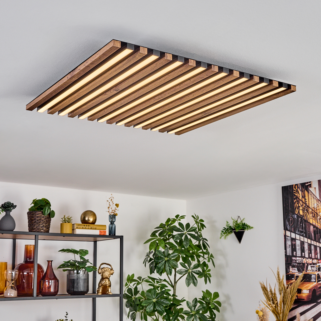 Moderne Deckenleuchte mit Holzlatten und integrierten Lichtern. Darunter Pflanzen, Regale mit Deko und ein Wandgemälde.