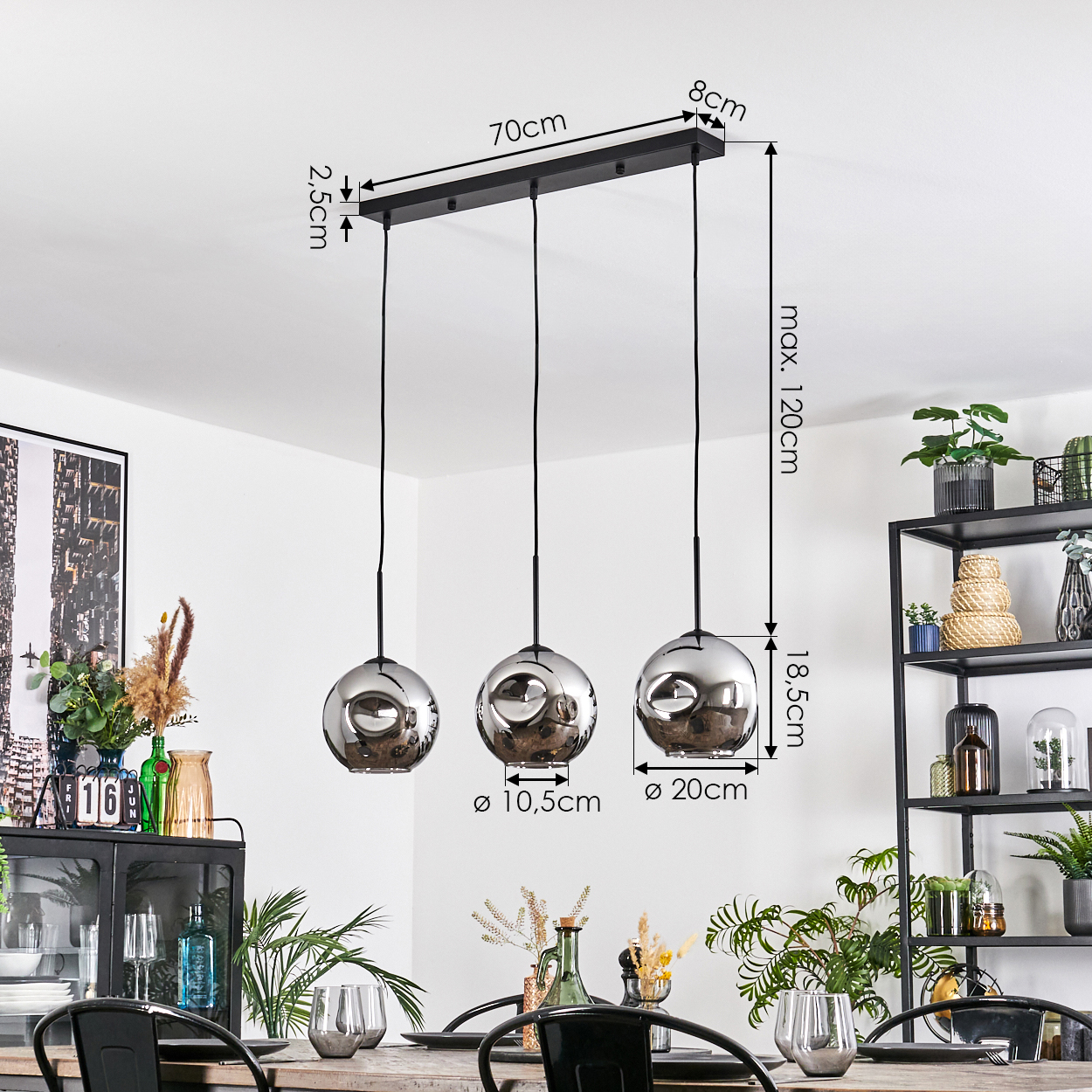 Ein modernes Esszimmer mit einer schwarzen Metall-Deckenleuchte mit drei kugelförmigen Lampen. Der Tisch ist gedeckt mit Gläsern und Pflanzen.
