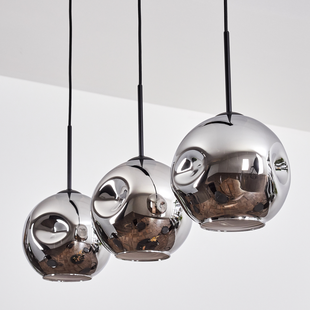 Drei verchromte kugelförmige Pendelleuchten hängen von der Decke. Die Kugeln reflektieren den Raum, mit schwarzen Kabeln.