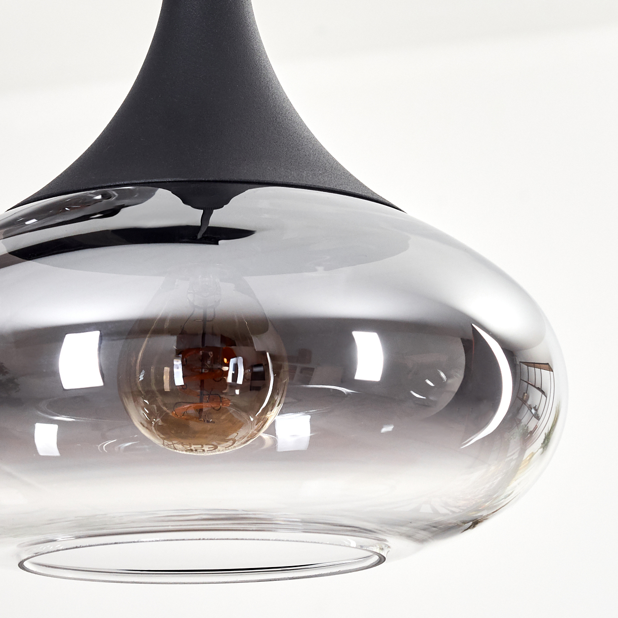 Eine moderne Pendelleuchte mit schwarzem Oberteil und grauem Glasschirm. Eine Glühbirne ist im Schirm sichtbar.