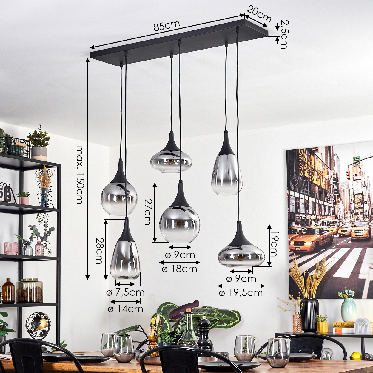 Ein modernes Esszimmer mit einem schwarzen, rechteckigen Kronleuchter mit 5 metallischen Lampen. Ein Tisch ist mit Gläsern und Pflanzen gedeckt.