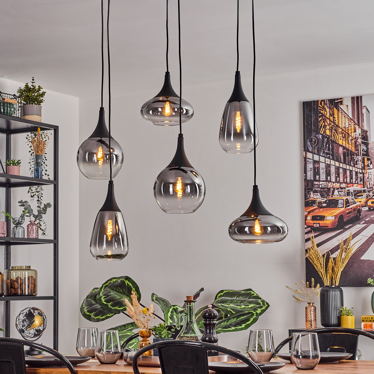 Esszimmer mit Pendelleuchten. Tisch mit Gläsern und Pflanzen. Im Hintergrund ein New Yorker Straßenkunstwerk.