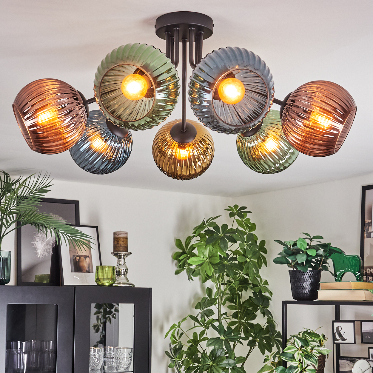 Eine moderne Deckenlampe mit Glasschirmen, mehreren Pflanzen und Dekorationen. Die Lampe hat sechs Lichter mit bunten Glasschirmen.