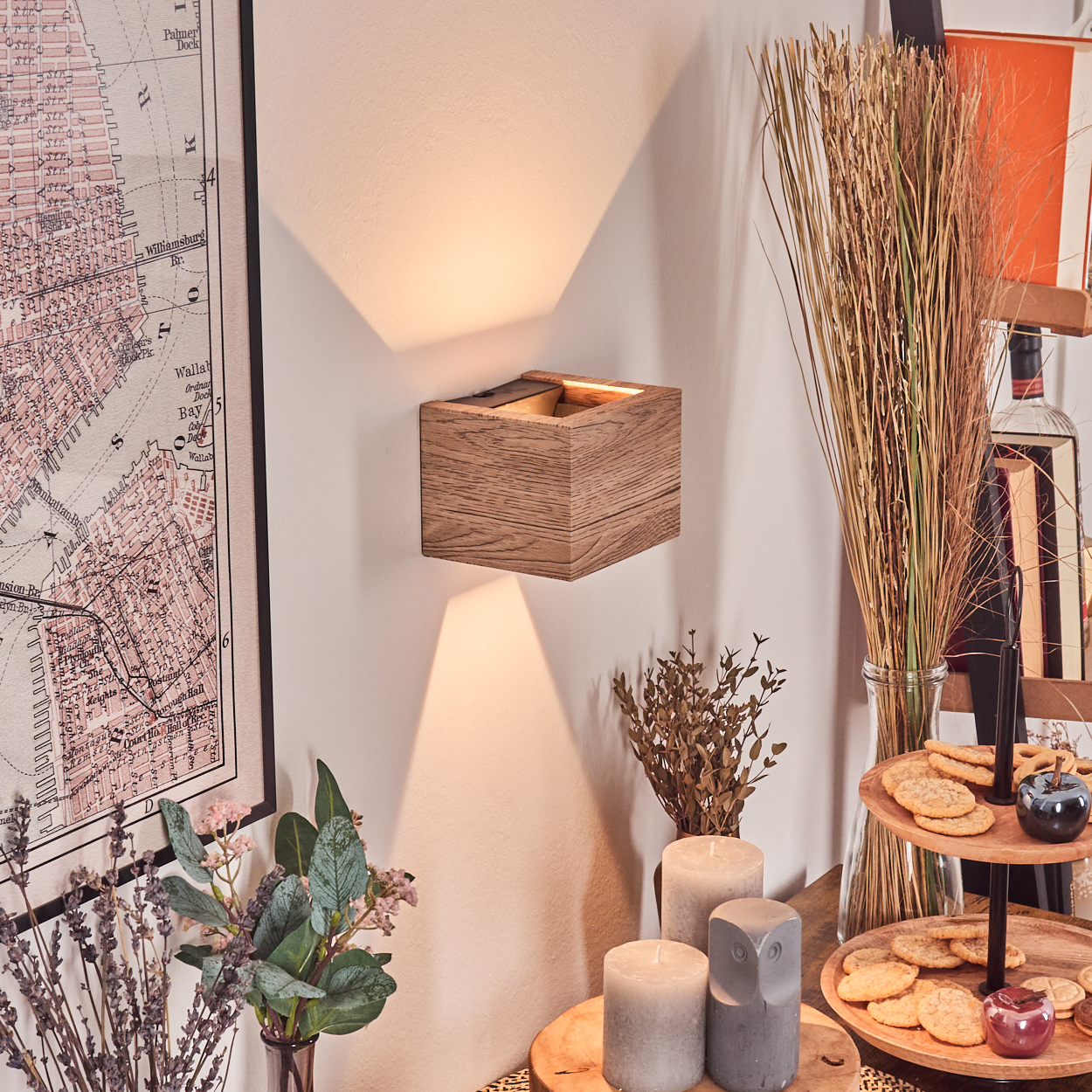 Eine Holz-Wandleuchte beleuchtet eine Wand. Eine Karte, Blumen, Kerzen, Kekse und andere Dekorationen umgeben die Lampe.