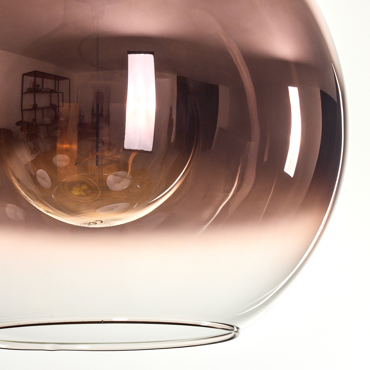 Nahaufnahme einer Glaskörper-Leuchte, kugelförmig. Das Glas hat einen Farbverlauf von Braun zu Klar. Reflexionen sind sichtbar.