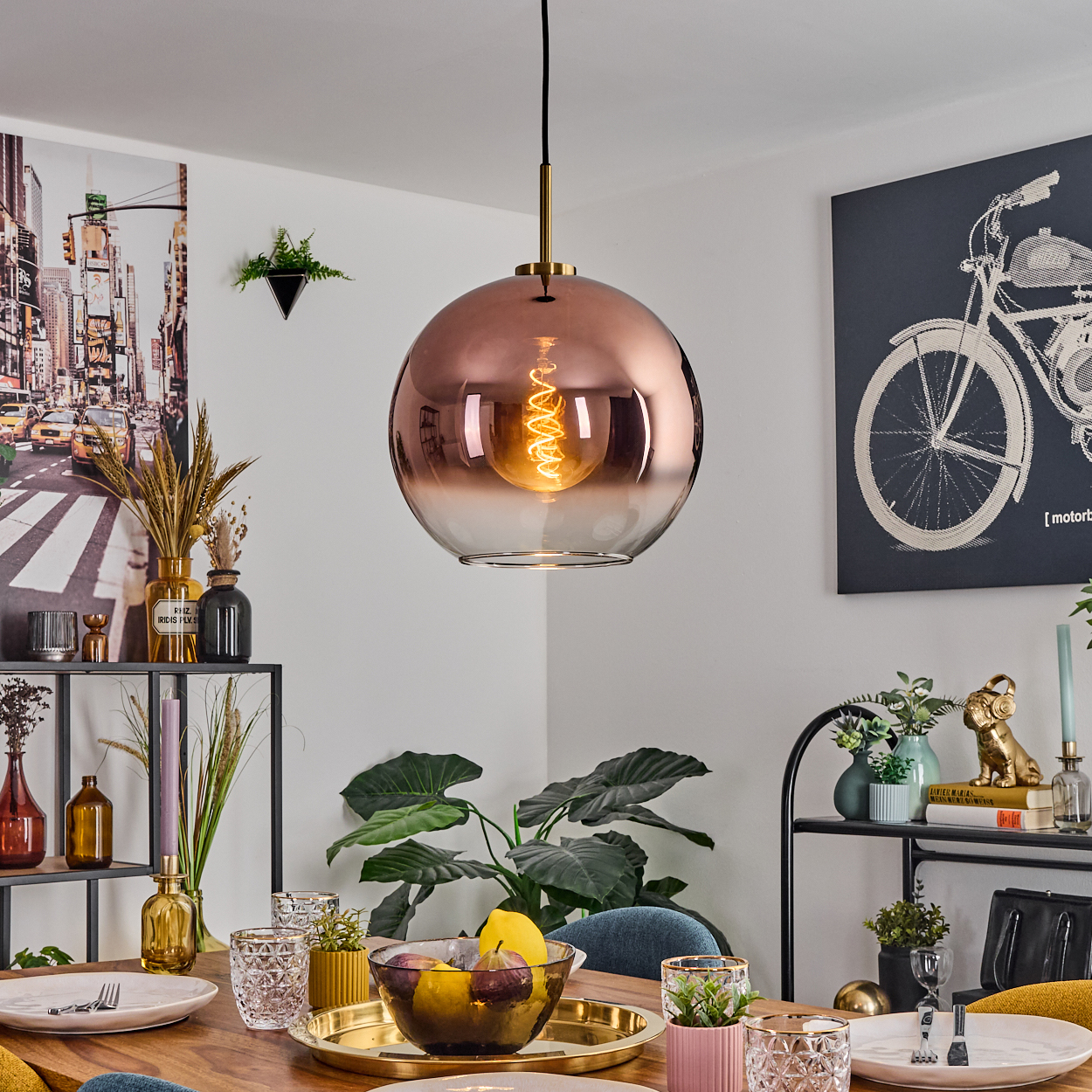 Ein Esszimmer mit einer kupferfarbenen Kugelleuchte, einem Tisch mit Tellern und einer Vielzahl von Dekorationsgegenständen.