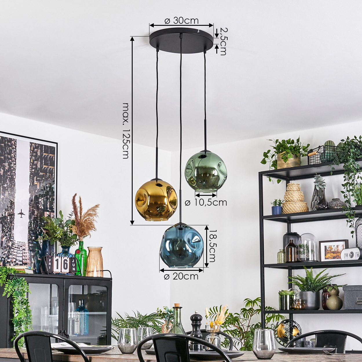 Drei Pendelleuchten mit Glaskugeln hängen von der Decke. Darunter ist ein Esstisch, im Hintergrund ein schwarzes Metallregal.