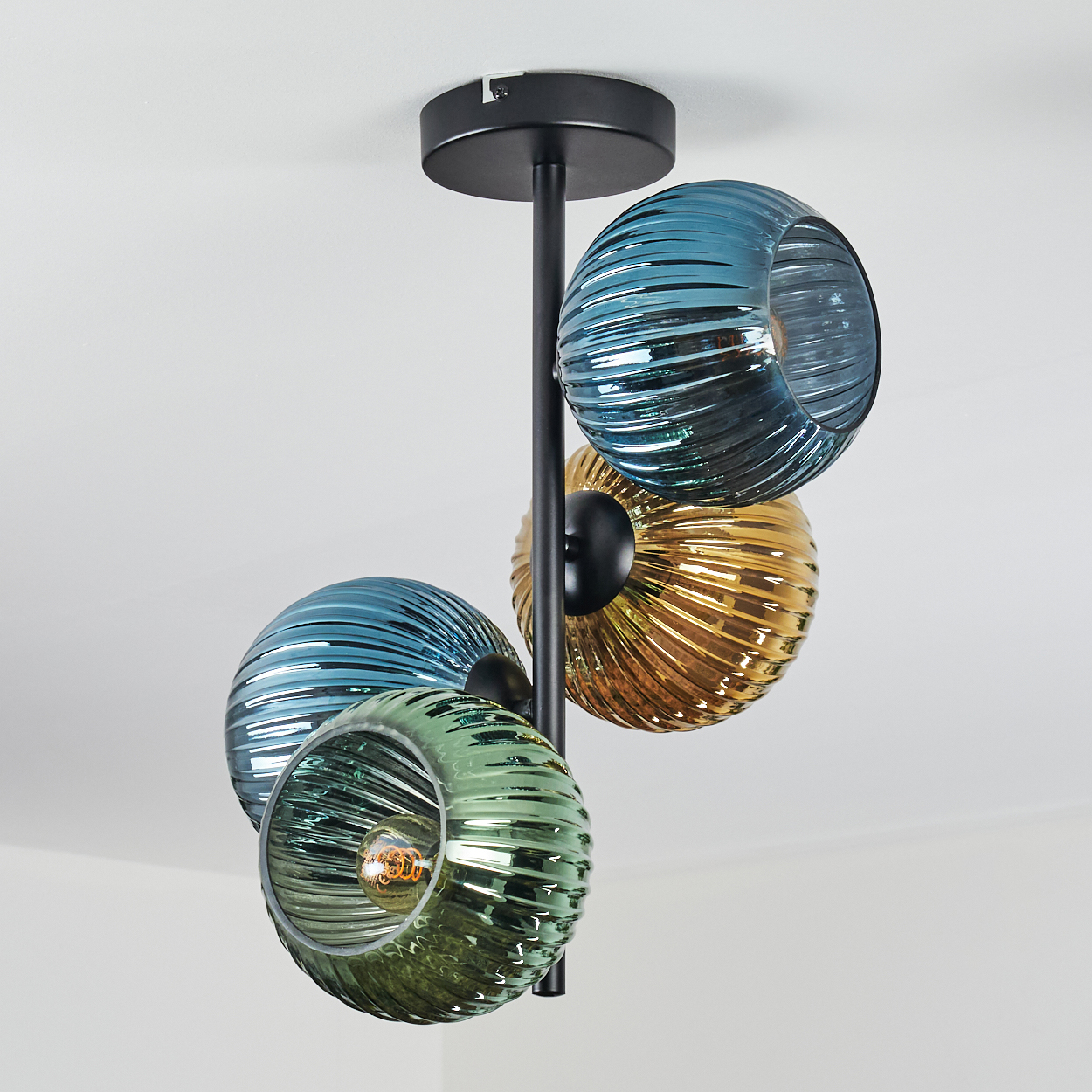 Moderne Deckenleuchte mit vier Glaskugeln in Blau, Grün und Gold. Schwarzes Metall stützt die Kugeln.