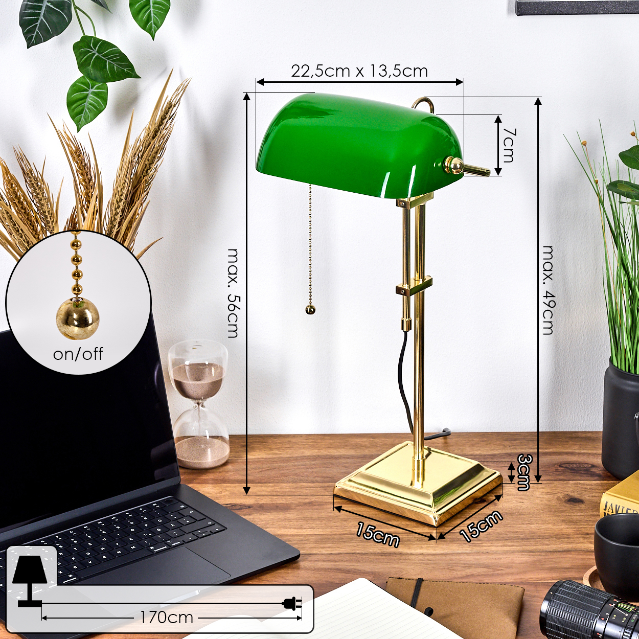 Eine grüne Schreibtischlampe mit goldenen Details steht auf einem Holzschreibtisch mit Laptop und anderen Objekten.
